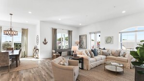 A spacious living room with a large sectional sofa, a dining area with a table and chairs, and a chandelier. - Gulf Place Residences #307 by Southern Vacation Rentals (Santa Rosa Beach)