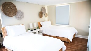 A bedroom with two beds, a bedside table with a lamp, and decorative wall hangings. - 3BR/2BA Chic and Tranquil Magnolia House Near Boston (Everett)