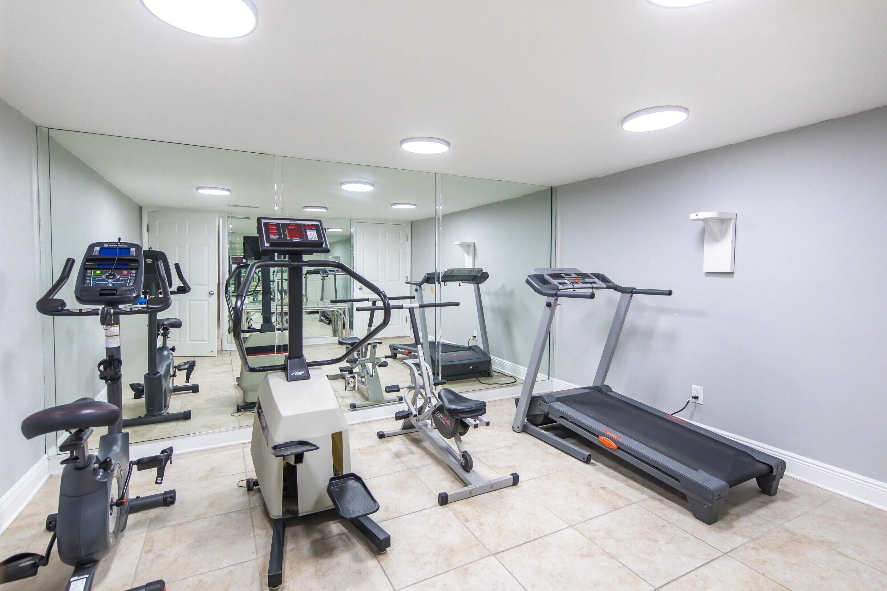 A gym with various exercise equipment including treadmills, stationary bikes, and weight machines.