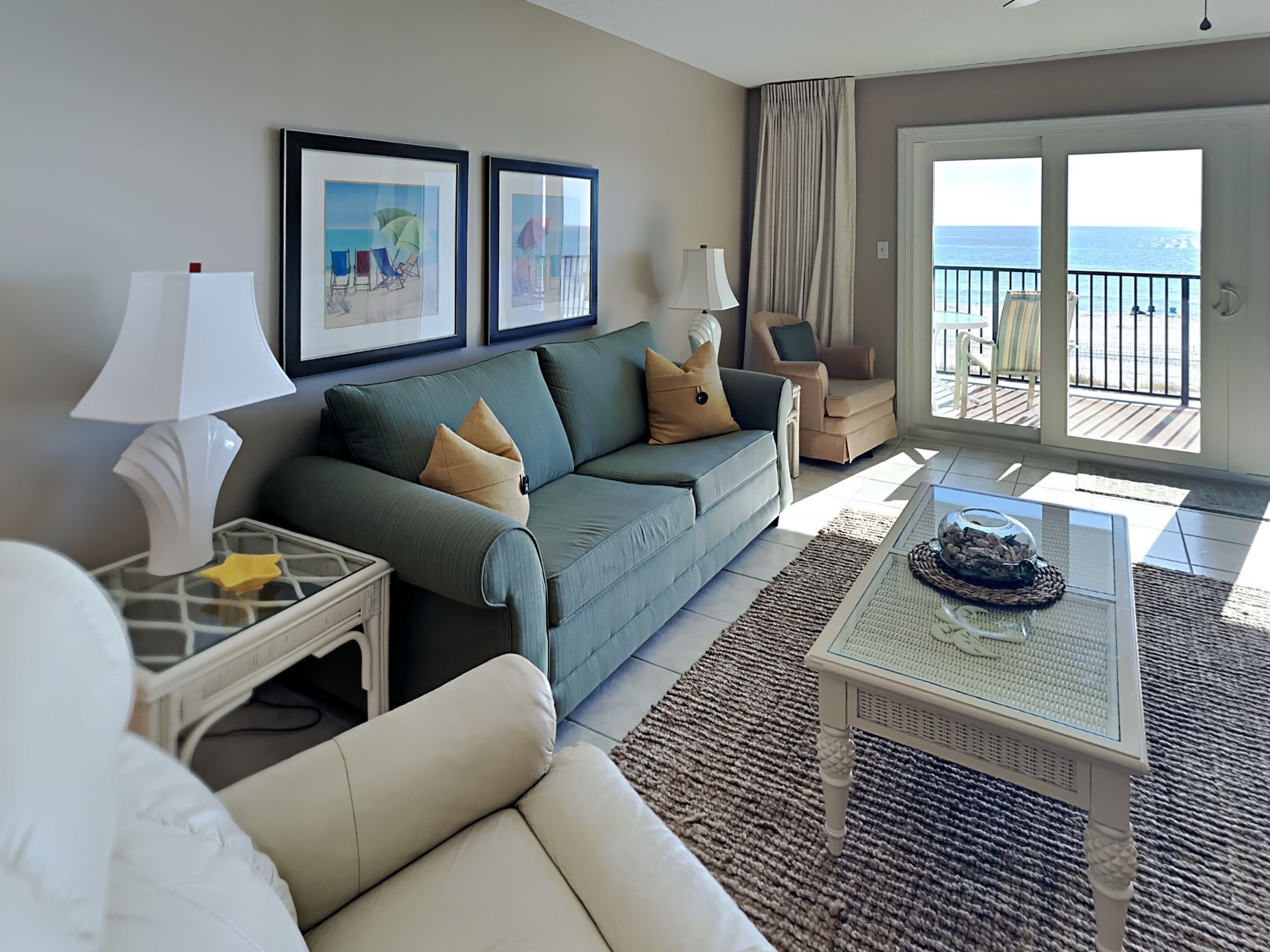 Un salon comprenant un canapé, des fauteuils, une table basse et un balcon avec vue sur la mer.
