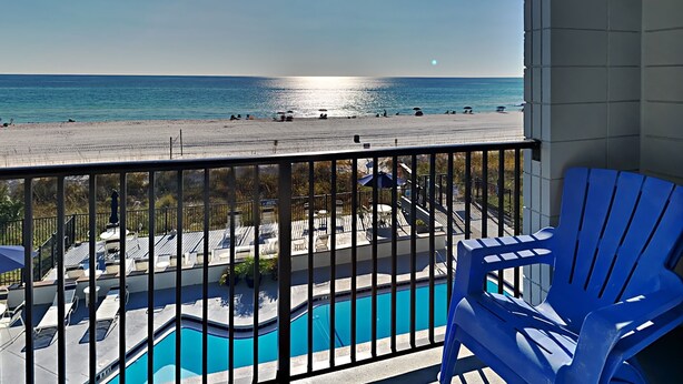 Un balcon avec vue sur une plage et une piscine.