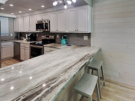 A modern kitchen with white cabinets, a marble countertop, and a built-in oven.