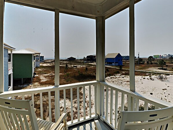 En inglasad veranda med utsikt över en strand och hus.