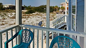 A beach house with a porch, two chairs, and a view of the beach and ocean. - Seahawk South B by Southern Vacation Rentals (Gulf Shores)