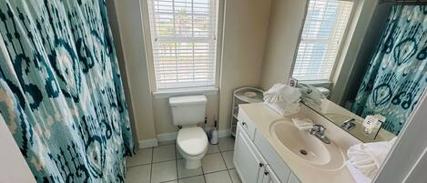 A bathroom with a toilet, sink, and a shower curtain.