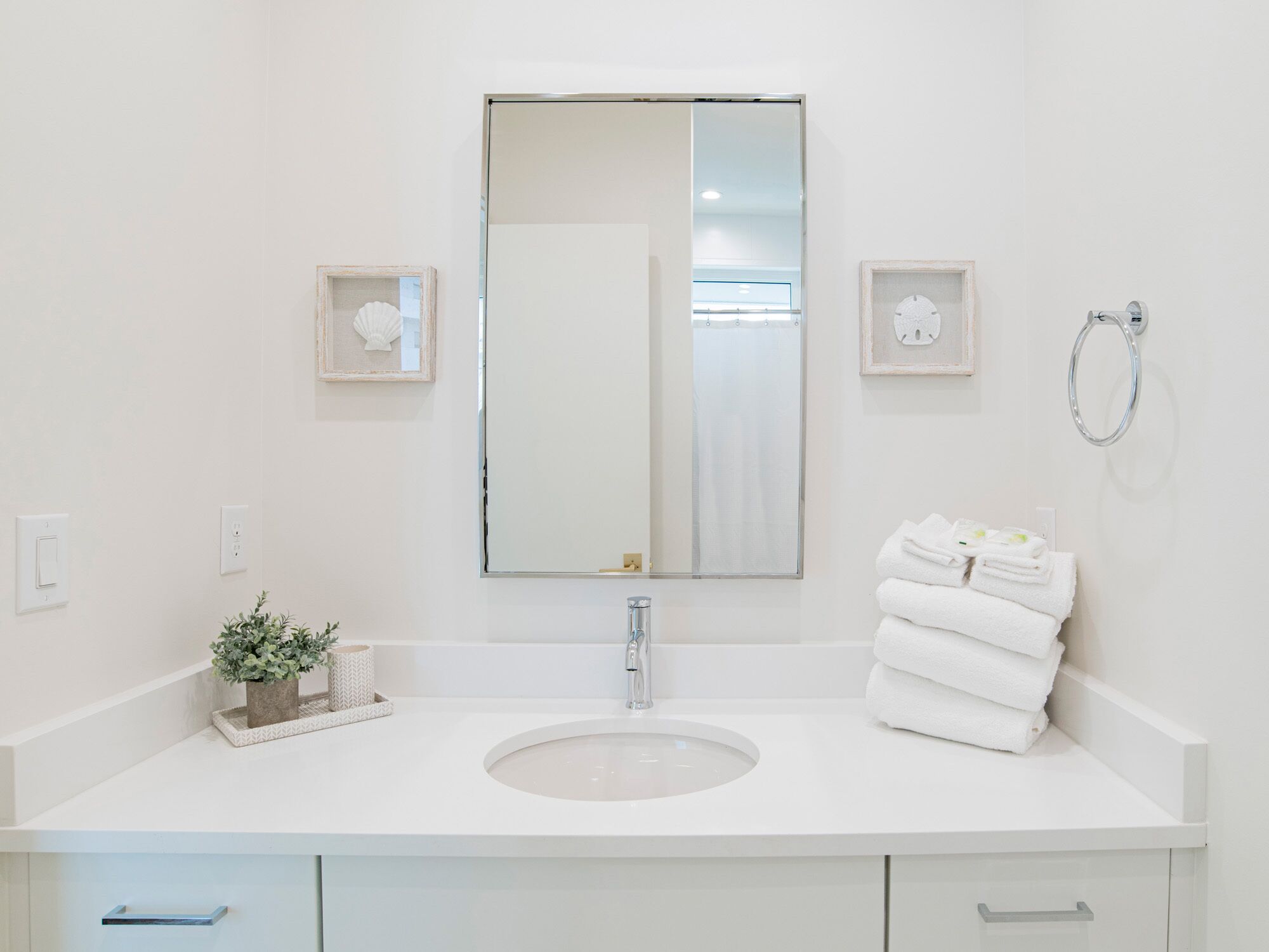 A modern bathroom with a white sink, a large mirror, and a towel rack.