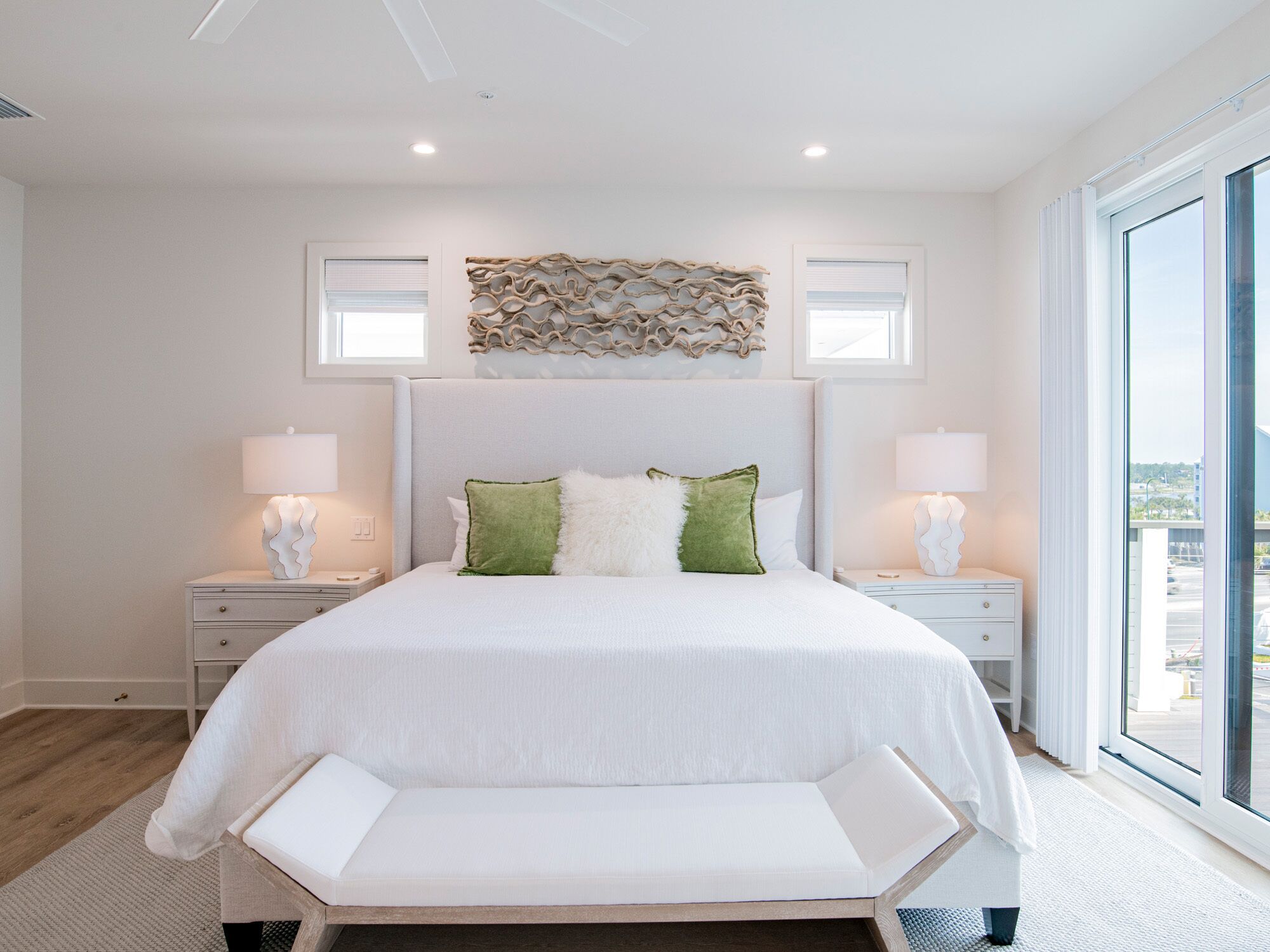 A modern bedroom with a large bed, two bedside tables, and a bench at the foot of the bed.