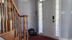 A hallway with a wooden staircase, a red carpet, and a white door with a window. - Baycation home with Hottub (Lewisporte)