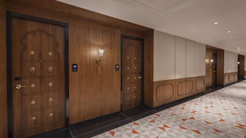 A hotel corridor with wooden doors, a patterned floor, and a light fixture.