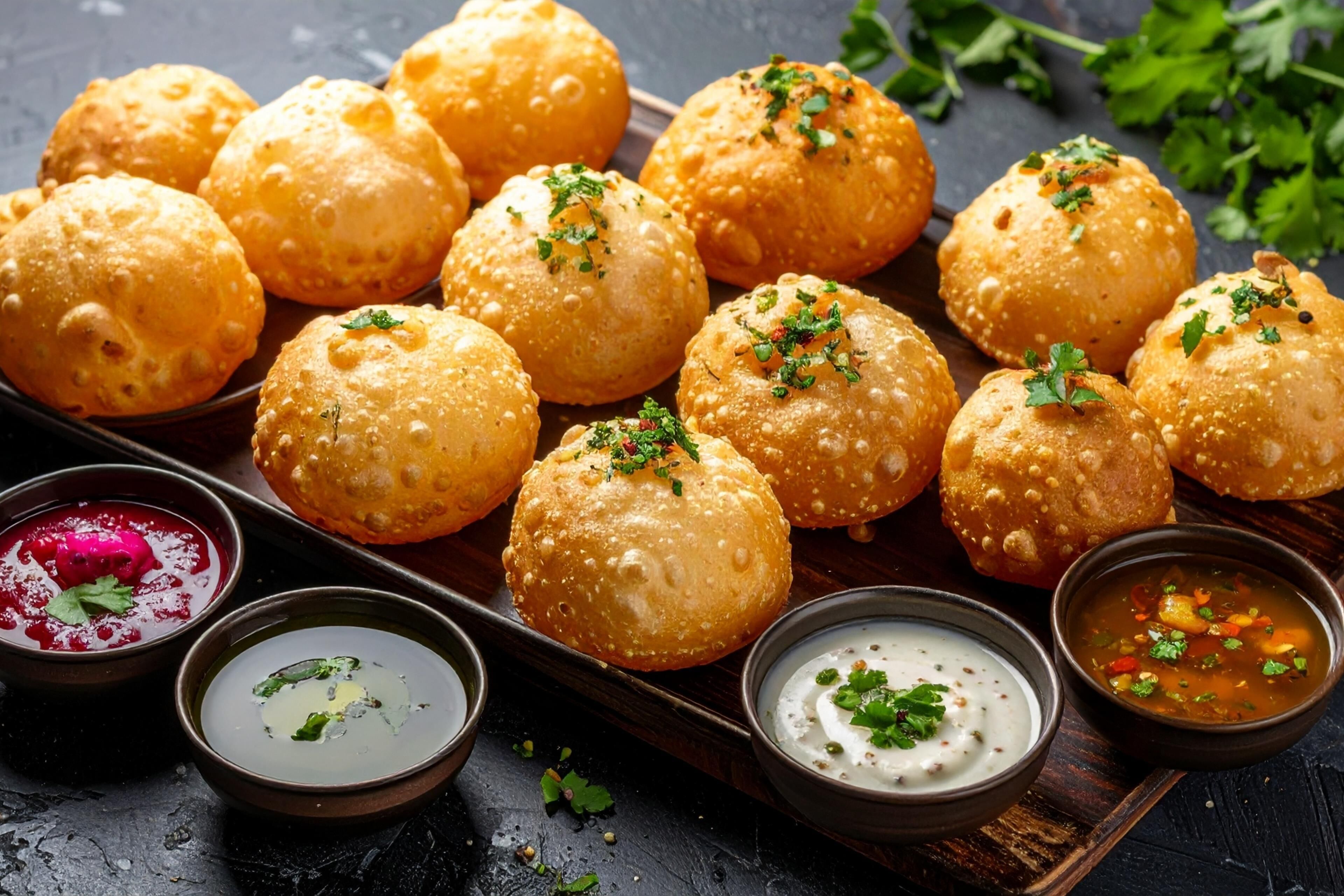 A tray of golden-brown fried balls garnished with herbs, accompanied by three small bowls of dipping sauces.