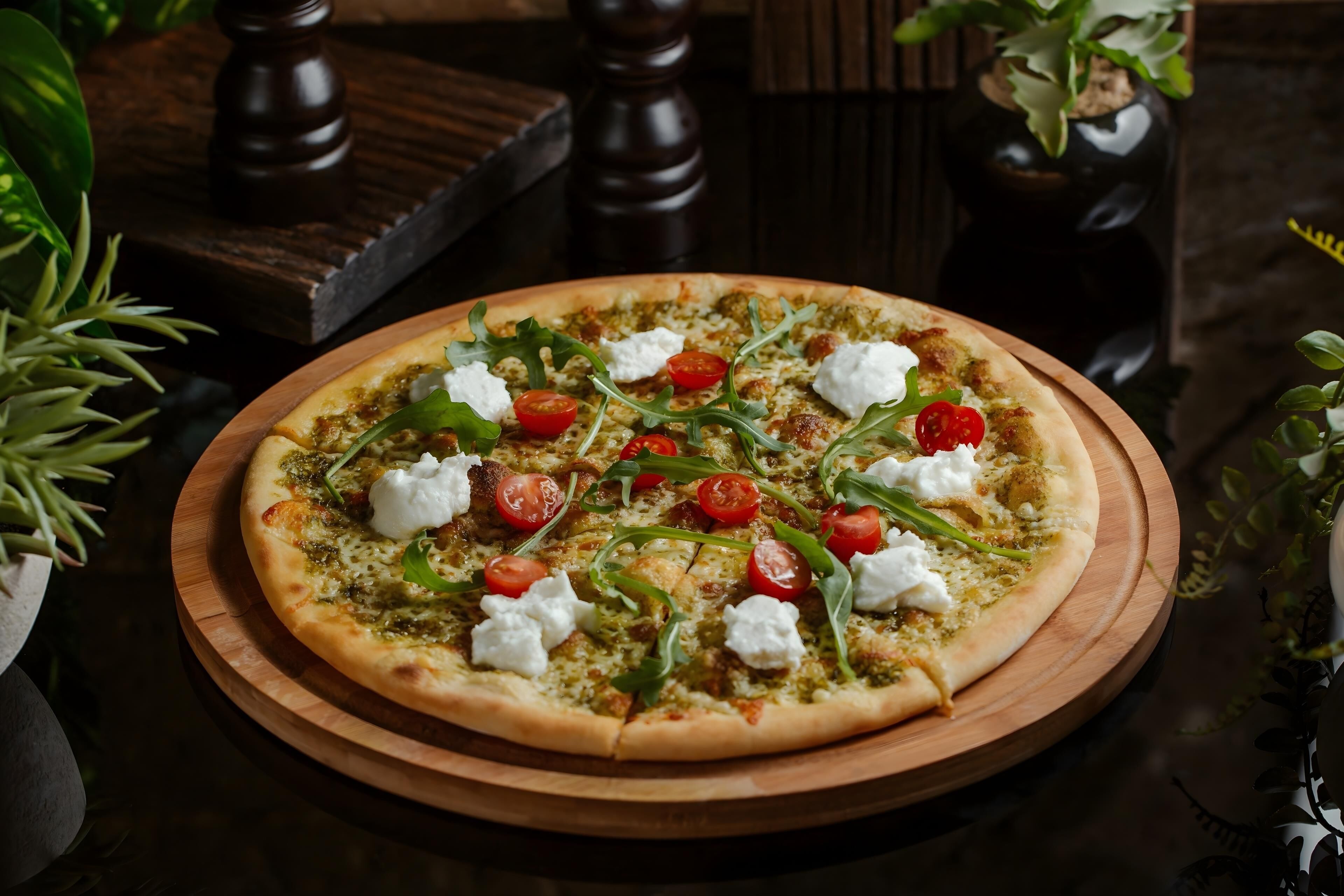 A pizza on a wooden board with toppings like tomatoes, cheese, and greens.
