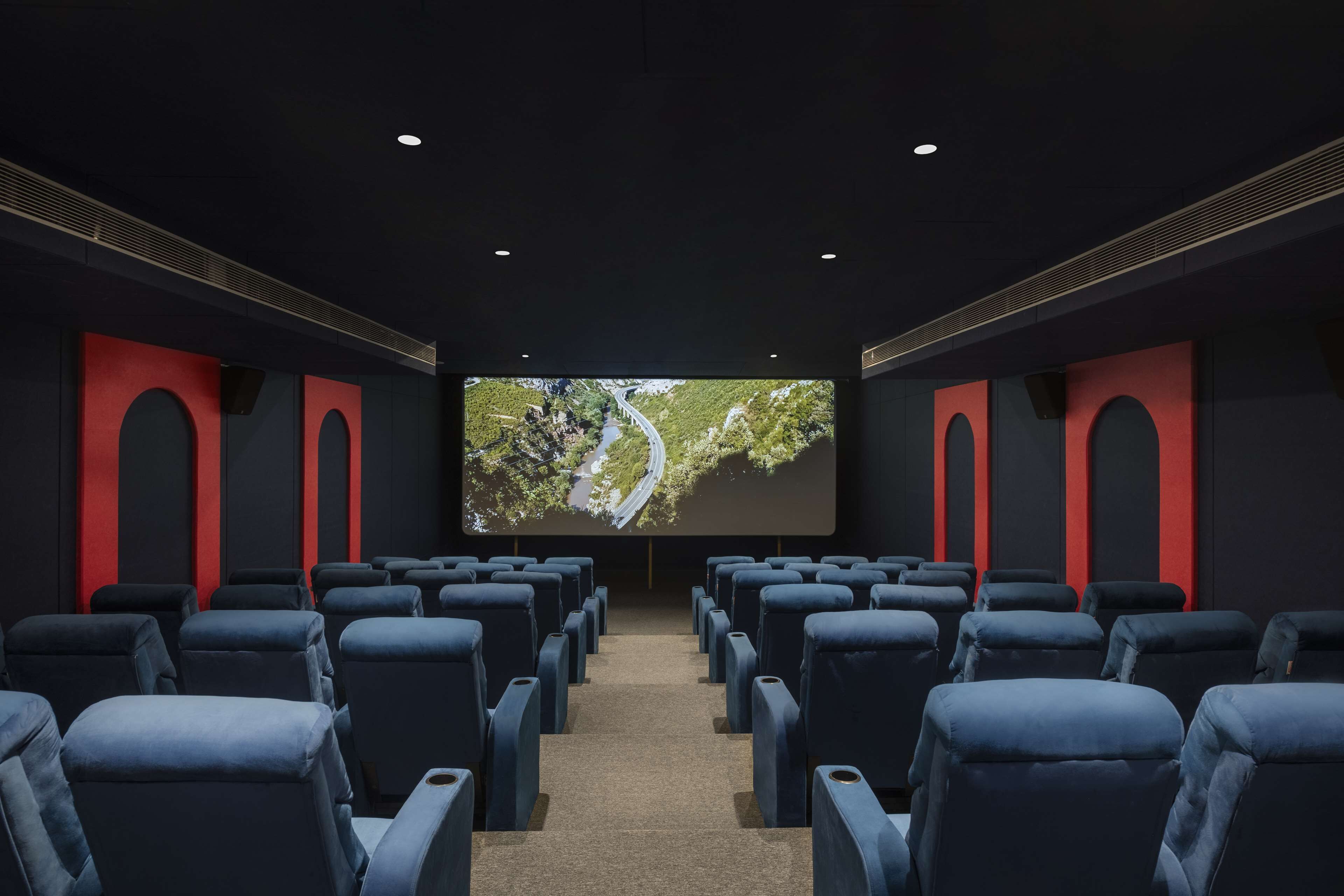 A movie theater with rows of seats facing a large screen.