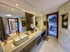 Un bagno moderno con uno specchio grande, due lavabi e una pianta di orchidea decorativa.