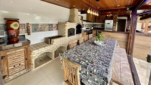 Una cucina con forno a mattoni, mobili in legno e un lungo tavolo da pranzo.