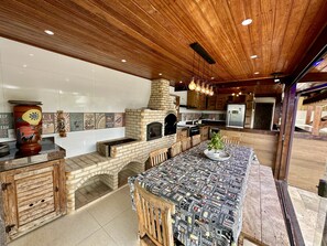 Una cocina con horno de ladrillo, armarios de madera y una larga mesa de comedor.