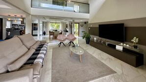 Un'ampia zona giorno con divano, tavolino e televisore. È presente un balcone con vista sul verde.