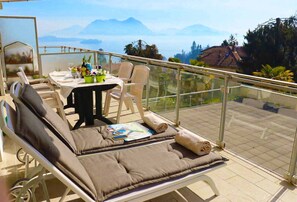 Ein Balkon mit Sitzgelegenheit, einem Tisch mit Getränken und einer Speisekarte und einem herrlichen Bergblick.
