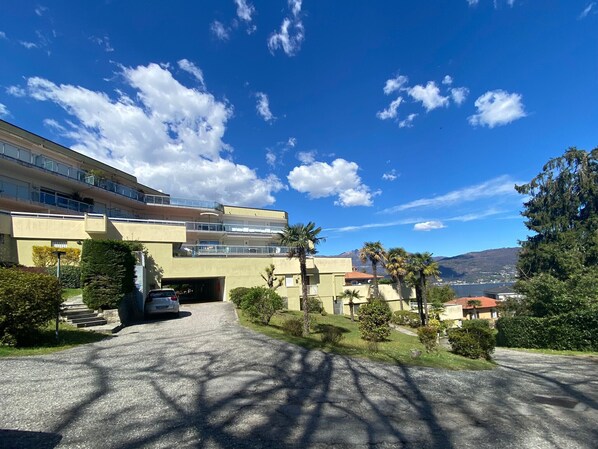 Ein modernes Gebäude mit mehreren Stockwerken, einem Parkplatz und Blick auf ferne Berge.