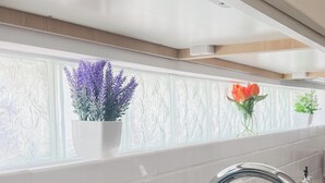 Une cuisine avec un rebord de fenêtre où sont posées des plantes en pot, un évier en acier inoxydable et un appareil électroménager de couleur turquoise.