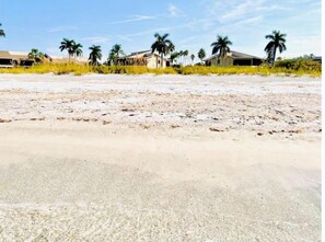Een strand met meerdere gebouwen, waarvan enkele met palmbomen in de buurt.