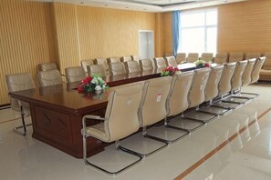 Uma sala de conferências com uma mesa comprida, várias cadeiras e uma janela com cortinas.