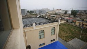Un edificio de gran altura con varios balcones, techo plano y vista de edificios circundantes.