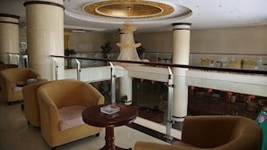 Un vestíbulo con candelabro, zona de estar y barandilla de vidrio.