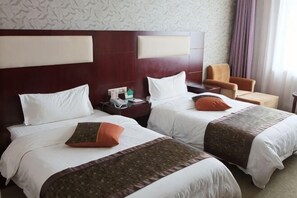 A hotel room with two beds, a nightstand, a chair, and a small table. - Golden World International Hotel (Dulan)