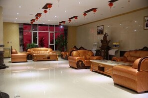 Um hall amplo com sofás de couro, uma mesa de centro de mármore e grandes janelas.