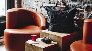 A modern interior with a brick wall, leather armchairs, a wooden coffee table, and a black handbag. - Le Petit Hôtel Vieux-Montréal | Notre-Dame (Montreal)