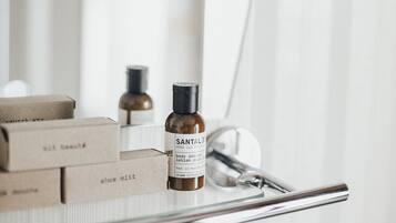 A bathroom vanity with a mirror, a bottle of Santal body lotion, and a pair of scissors.