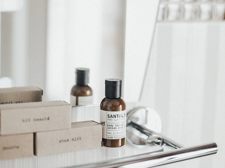 A bathroom vanity with a mirror, a bottle of Santal body lotion, and a pair of scissors.