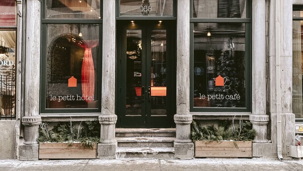 A historic building with a classic facade, large arched windows, and a prominent entrance. - Le Petit Hôtel Vieux-Montréal | Notre-Dame (Montreal)