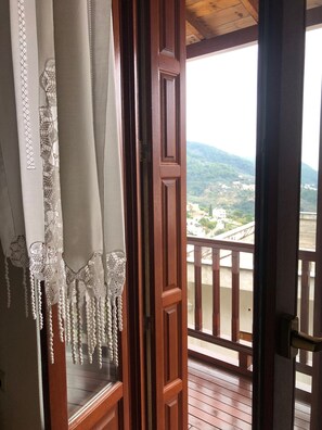 Una porta in legno che dà su un balcone e un paesaggio montano.