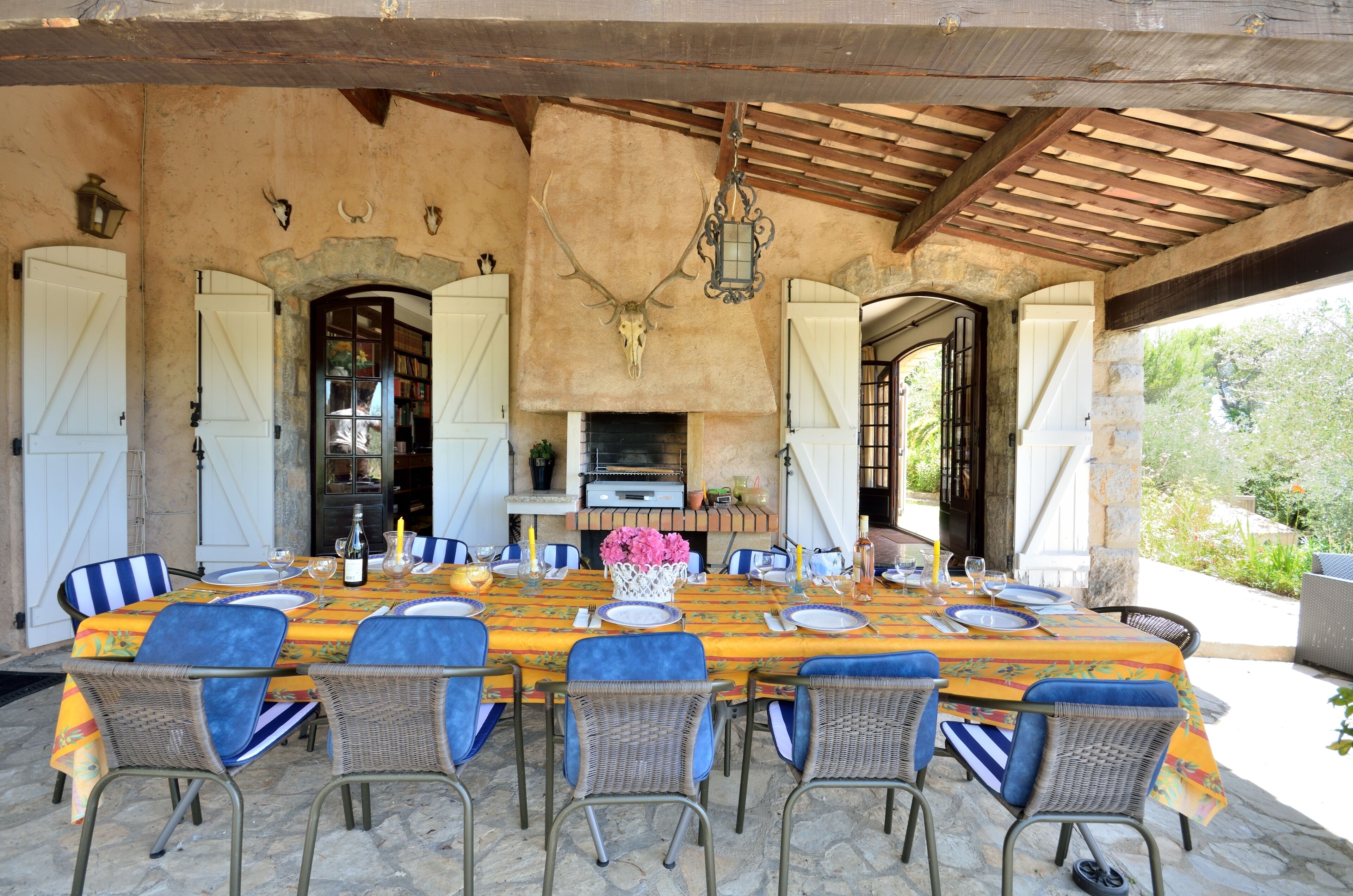 An outdoor dining area with a long table set for six, surrounded by wicker chairs.