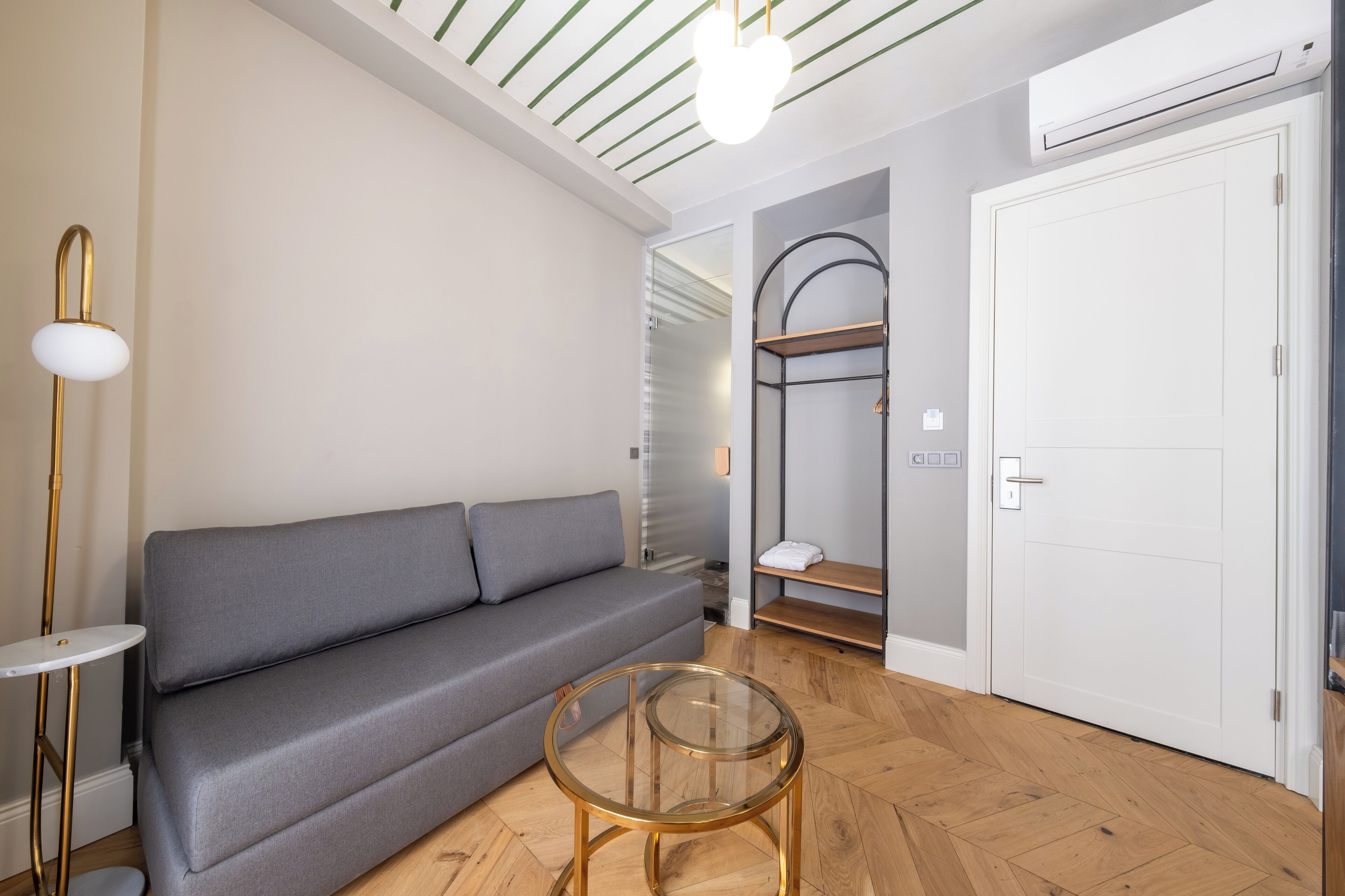 En moderne stue med en grå sofa, et glasbord og et hvidt skab.