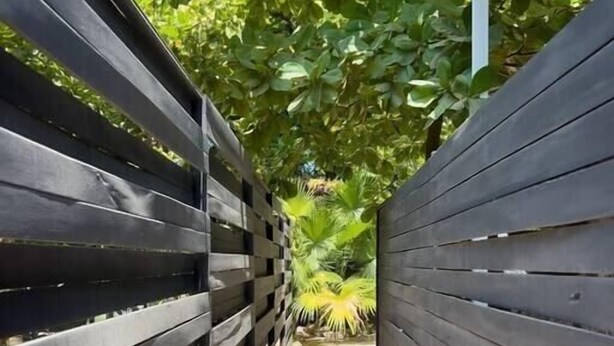 Un sendero bordeado por vallas de madera y vegetación en la parte superior.