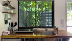 Una cocina moderna con un amplio ventanal, un fregadero y diversos utensilios de cocina sobre la encimera.