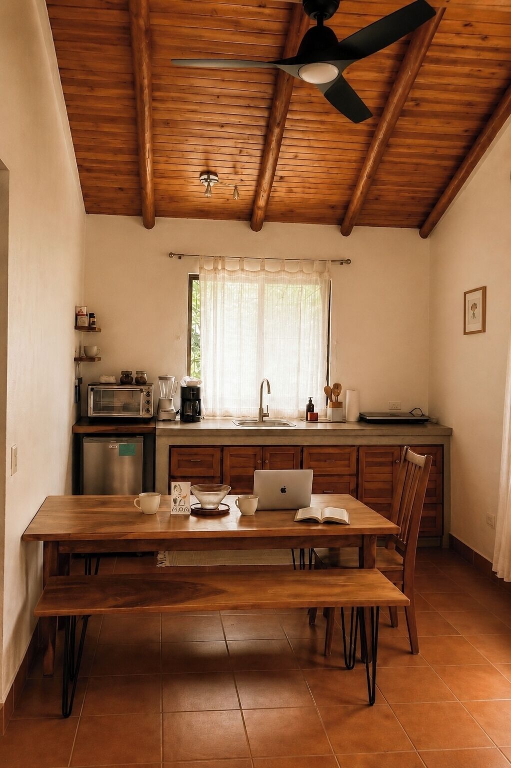 Una cucina con soffitto in legno, un tavolo da pranzo con sedie, un forno a microonde e un lavello.