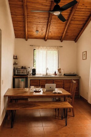 Une cuisine avec un plafond en bois, une table à manger avec des chaises, un four à micro-ondes et un évier.