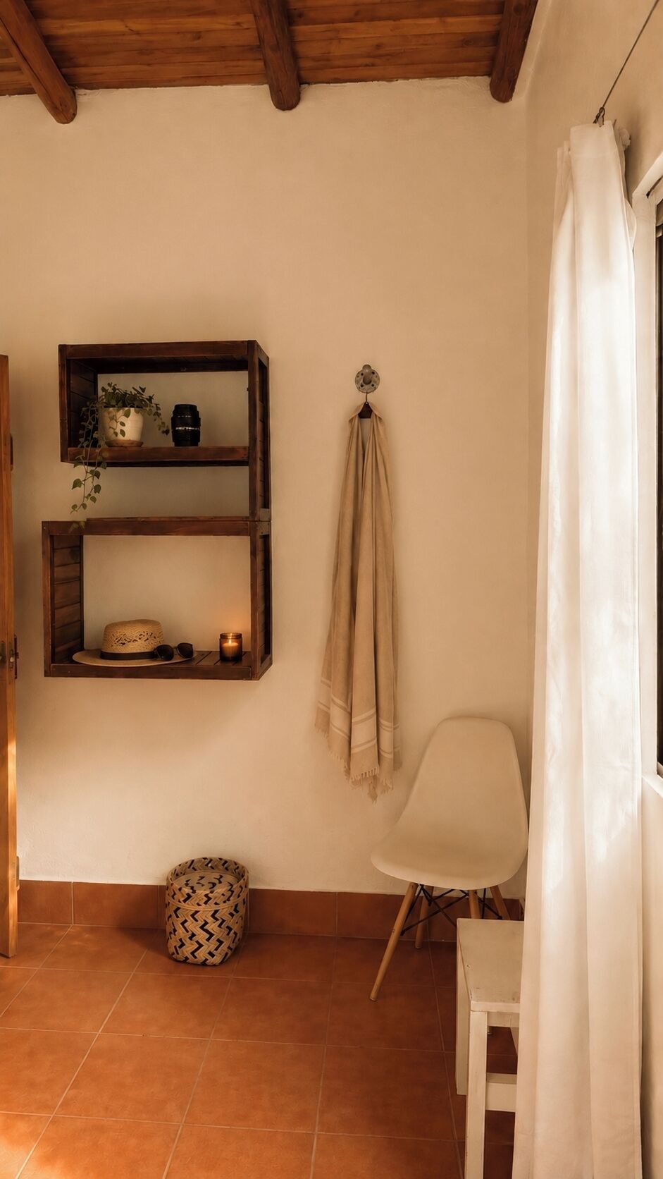 A room with a wooden ceiling, a white chair, a shelf with decorative items, and a hanging cloth.