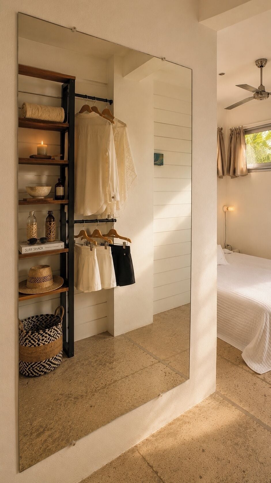 A bedroom with a bed, a ceiling fan, a window with curtains, and a wardrobe with hanging clothes.