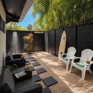A patio with outdoor seating, a surfboard, and a water feature.