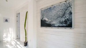 Un couloir avec un cactus, une œuvre d’art encadrée et une porte.