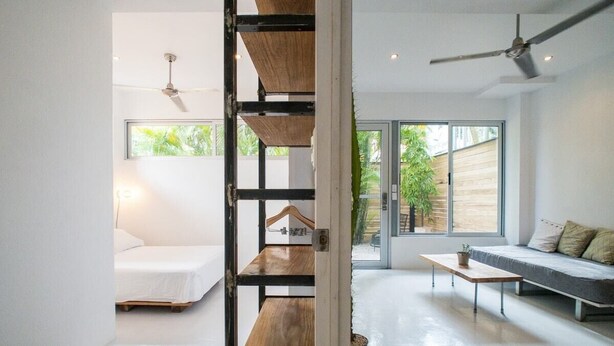 Un intérieur moderne comprenant un lit, une étagère en bois, un banc et un canapé.