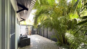 Un espace extérieur abrité, doté d’un sol en gravier, de mobilier d’extérieur noir et d’une végétation luxuriante.