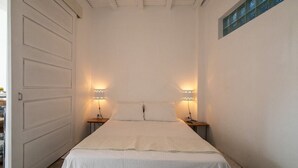A bedroom with a bed, two bedside tables, and two wall-mounted lamps.