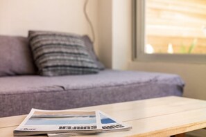 Una revista sobre una mesa de madera, con un sofá y una ventana al fondo.