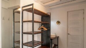 A room with a metal shelving unit, a small table with a sink, and a door.
