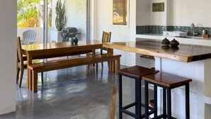Een moderne keuken met een groot eiland, een houten eettafel en stoelen.
